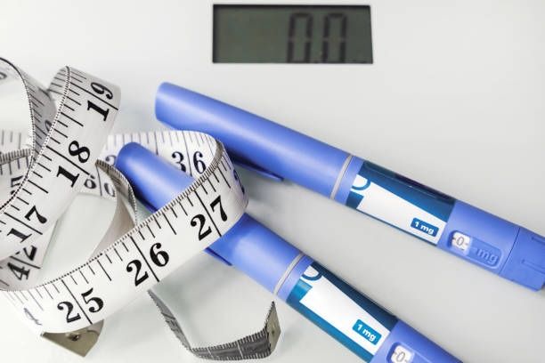 Concepto de pérdida de peso con plumas de inyección etiquetadas 1 mg, cinta métrica y báscula digital que marca cero