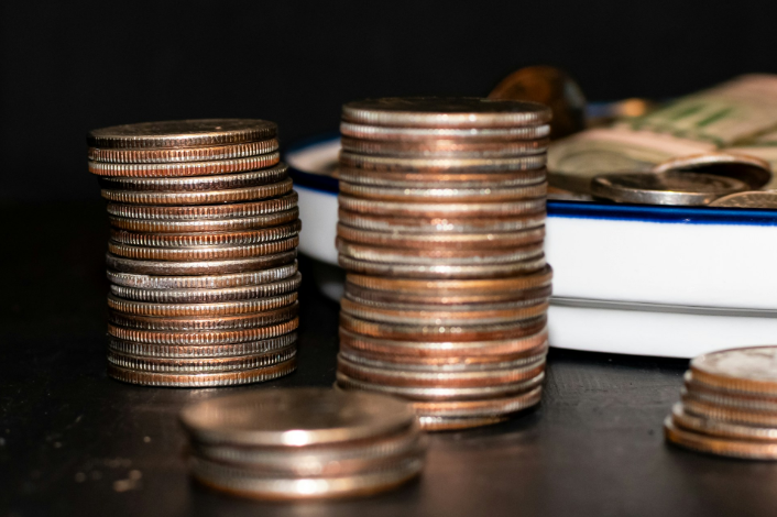 Dos pilas de monedas de veinticinco centavos frente a un plato azul y blanco